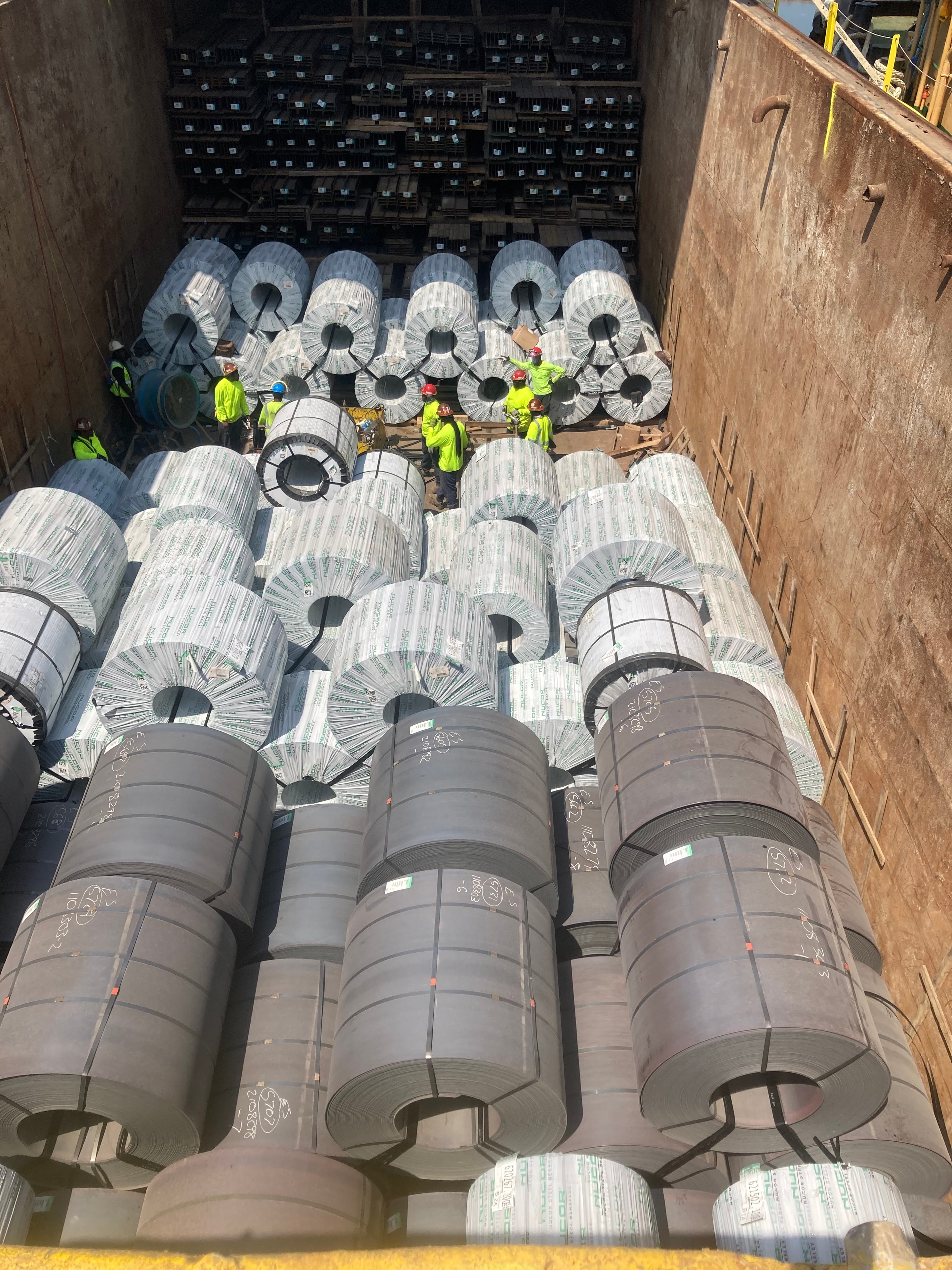 Survey crew inspecting steel coil cargo in ship hold